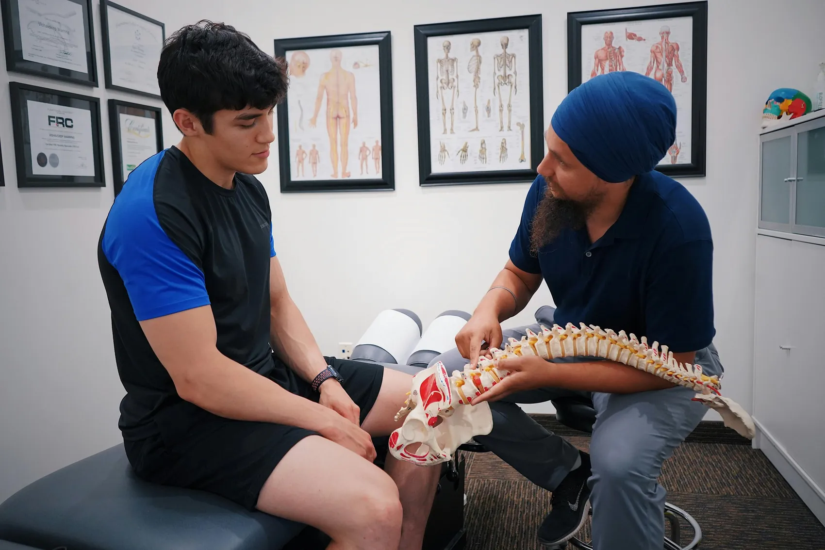 A practitioner showing a patient a model of the spine